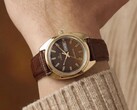 Timex Q 1978 Day and Date met een bruine fuméwijzerplaat en goudkleurige kast, getoond om een pols met een bruine leren band.