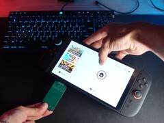 Yu van het YouTube-kanaal Better Gaming met in zijn ene hand een Nintendo Switch 2 en in zijn andere hand een open-source groene PCB-adapter, die hij in de microSD Express-sleuf van het apparaat probeert te steken (bron: Better Gaming via YouTube)