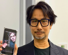 Hideo Kojima toont een poster van Physint op zijn telefoon