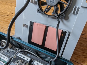 Elke SSD-sleuf heeft zijn eigen thermische pad bevestigd aan een groter koellichaam op de ventilatorbeugel