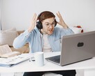 Man met een koptelefoon die gefrustreerd zijn handen opheft voor een laptop