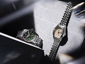 De Seiko 5 Sports Field GMT HDB001 met een groene wijzerplaat en de HDB002 met een crèmekleurige wijzerplaat, naast elkaar gepresenteerd aan roestvrijstalen armbanden met vijf schakels, beide voorzien van een vaste 24-uursring en een oranje GMT-wijzer.