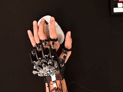 Een doe-het-zelf exoskeletapparaat vastgebonden aan een hand tijdens het gebruik van een gamingmuis (Afbeelding bron: Basically Homeless/YouTube)