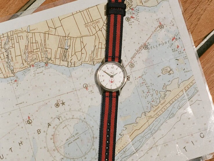 Noah x Timex MK1 Anchor-horloge met een marineblauw-rood gestreepte stoffen band, rustend op een zeekaart.