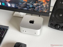 Een Apple M6 Mac mini op een bureau in een gamingopstelling met een monitor, toetsenbord, muis en luidspreker.
