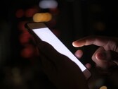 Een hand die in het donker een smartphone met een verlicht scherm vasthoudt