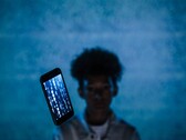 Zwevende smartphone met code op het scherm tegen een blauwe achtergrond, met een onscherpe persoon erachter