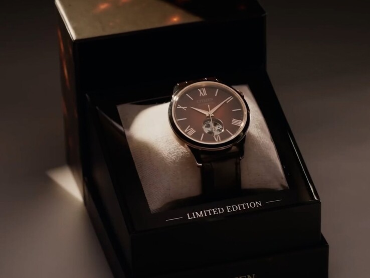 Een breder, dramatisch belicht beeld van het Citizen-horloge dat op een kussentje in zijn donkere, getrapte presentatiedoos ligt. Een warme spotlichtstraal valt op de wijzerplaat, en op de onderste voorrand van de doos staat „CITIZEN“ gedrukt.