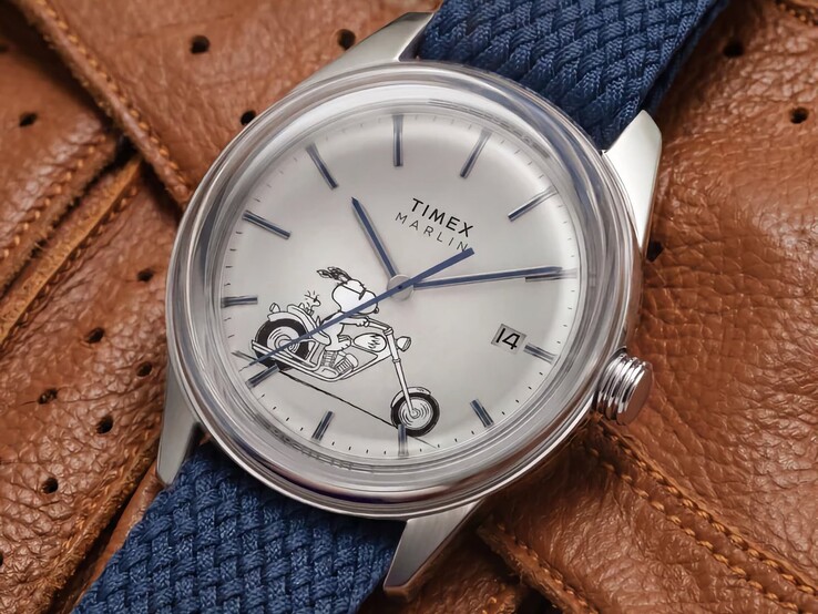 Schuine vooraanzichtfoto van de Peanuts x Timex Marlin Jet Automatic Easy Rider, waarbij de gewelfde glasplaat, de zilverkleurige roestvrijstalen kast, de wijzerplaat met Snoopy-motief en de blauwe stoffen band worden benadrukt.