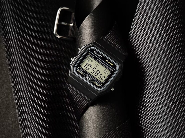 Casio F-91WF-1A digitaal horloge met een zwarte kast, een zwarte geweven stoffen band en zilveren accenten, gefotografeerd tegen een donkere, gestructureerde achtergrond.