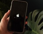 Een hand houdt een iPhone vast; op het scherm zijn het Apple-logo en een voortgangsbalk te zien.