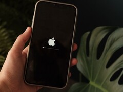 Een hand houdt een iPhone vast; op het scherm zijn het Apple-logo en een voortgangsbalk te zien.
