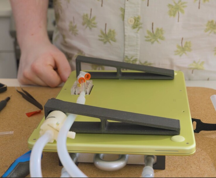 Aangepaste MacBook Neo met externe pomp en slangen voor doe-het-zelf vloeistofkoeling