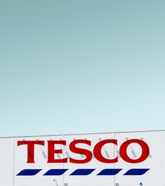 Buitenreclame Tesco gefotografeerd tegen een heldere hemel (Afbeelding bron: Simone Hutsch via Unsplash)