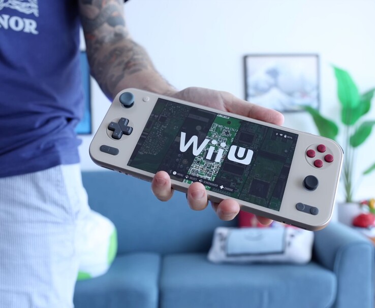 Russ van Retro Game Corps met de Ayaneo Pocket S2 handheld console waarop een Wii U emulator draait, met het apparaat prominent afgebeeld in een woonkamer. (Afbeelding bron: Retro Game Corps)