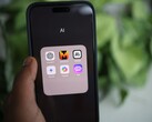 Een hand houdt een smartphone vast waarop een map met de naam „AI“ te zien is, met daarin apps zoals Gemini, ChatGPT en Claude