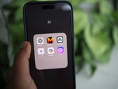 Een hand houdt een smartphone vast waarop een map met de naam „AI“ te zien is, met daarin apps zoals Gemini, ChatGPT en Claude