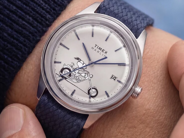De Peanuts x Timex Marlin Jet Automatic Easy Rider, gedragen om de pols, met op de zilverwitte wijzerplaat een afbeelding van Snoopy op een motorfiets, blauwe indexen en wijzers, en een blauwe geweven stoffen band.