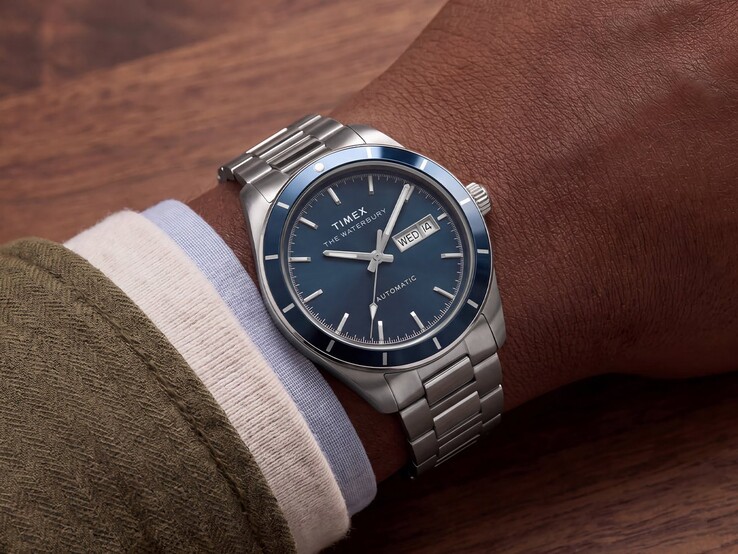 Een Timex Waterbury Heritage Automatic met een blauwe geëmailleerde wijzerplaat, gedragen om de pols, waarbij de zilverkleurige kast en de roestvrijstalen armband goed zichtbaar zijn.