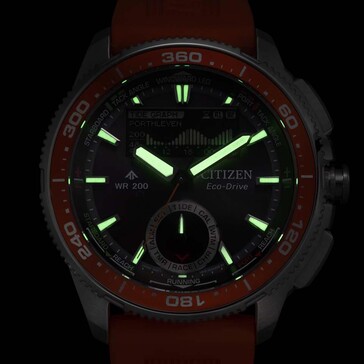 Low-light lume opname van de Citizen Promaster Wave Tracker JV3000-13E met oplichtende wijzers en uurmarkeringen tegen een donkere achtergrond.