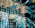 Blauwe glasvezelkabels met witte connectoren die zijn aangesloten op een patchpaneel in een datacenter