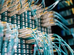 Blauwe glasvezelkabels met witte connectoren die zijn aangesloten op een patchpaneel in een datacenter
