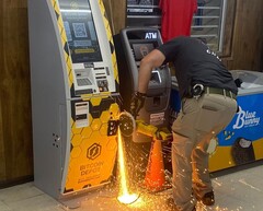 Een politieagent die met een handzaag in de Bitcoin geldautomaat snijdt (bron: Jasper County Sheriff&#039;s Office via Facebook; bijgesneden)