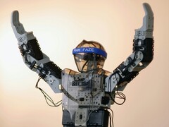 Een humanoïde robot met zijn armen in de lucht (Afbeelding bron: Adam Lukomski via Unsplash; bijgesneden)