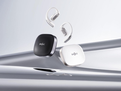 De Shokz OpenFit Pro (met hoesje), afgebeeld tegen een gestileerde zilveren achtergrond. (Afbeeldingsbron: Shokz)