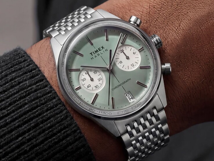 De Timex Marlin Jet Chronograph met een saliegroene wijzerplaat en een roestvrijstalen armband, gedragen om de pols, waarbij het gewelfde glas en het afgeronde, retro-futuristische profiel van de kast goed zichtbaar zijn.