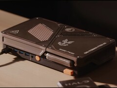 Een op maat gemaakte, compacte spelconsole met een mini-pc, zichtbare koelopeningen, USB-poorten en oranje aan/uit-knoppen op een bureau.
