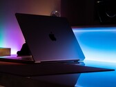 Een halfopen MacBook in een donkere kamer, waarbij licht door de opening op het bureau valt