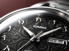 Close-up van de zwarte wijzerplaat van de Casio MTP-E735AR, met een verfijnd arabeskpatroon, opgelegde Oost-Arabische cijfers, gepolijste zilverkleurige wijzers en een dag-datumaanduiding op 3 uur.