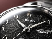 Close-up van de zwarte wijzerplaat van de Casio MTP-E735AR, met een verfijnd arabeskpatroon, opgelegde Oost-Arabische cijfers, gepolijste zilverkleurige wijzers en een dag-datumaanduiding op 3 uur.