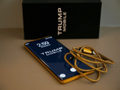 Een foto van de Trump Phone T1 naast de doos en kabel.