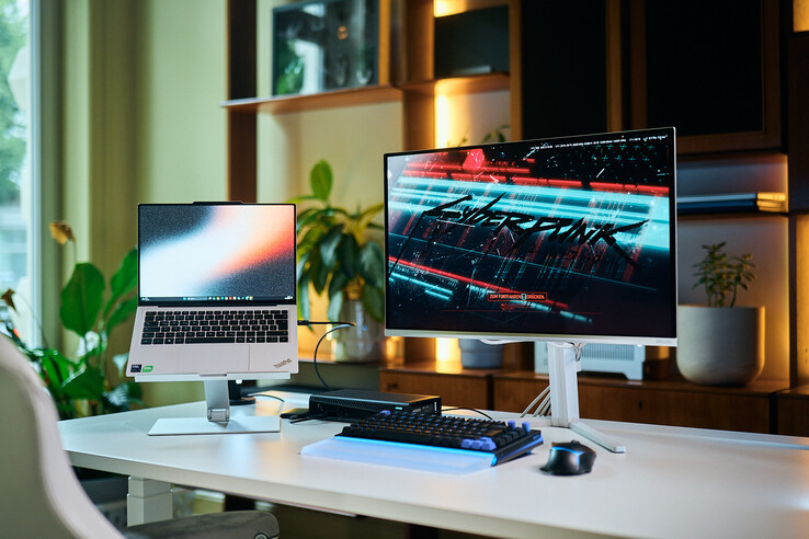 Een complete werkstationopstelling met een ThinkPad X9 14-laptop op een standaard, een Aorus RTX 5060 Ti AI Box eGPU en een externe monitor waarop Cyberpunk 2077 wordt weergegeven.