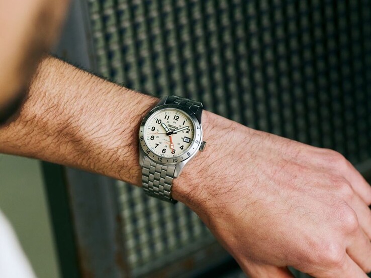 Een persoon die naar een Seiko 5 Sports Field-HDB002 met een beige wijzerplaat om zijn pols kijkt.