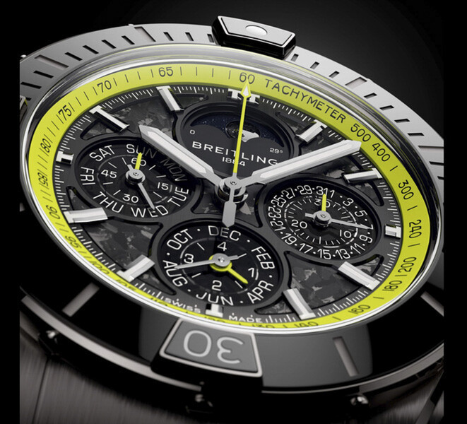 Close-up van de Breitling Super Chronomat B19 44 Perpetual Calendar Chronograph met zijn wijzerplaat van koolstofvezel, kalendersubwijzerplaten, zilverkleurige wijzers en limoengroene tachymeterschaal.