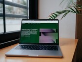 Een laptop op een bureau bij een raam, met de OpenAI ChatGPT-website geopend op het scherm