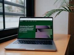Een laptop op een bureau bij een raam, met de OpenAI ChatGPT-website geopend op het scherm