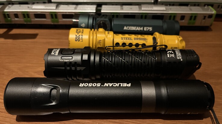 De gele SK-07 van Loop Gear vergeleken met de Acebeam E75 (achteraan), de Nitecore P27i en de Pelican 5050R