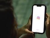 Vrouw die een smartphone met beide handen vasthoudt; op het scherm is het startscherm van Instagram te zien