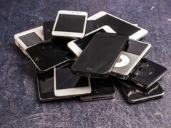 Een stapel afgedankte smartphones op een grijze ondergrond