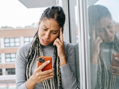 Een vrouw kijkt met een ernstige blik naar haar smartphone