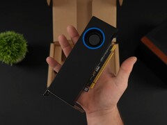 Een persoon die de Intel Arc Pro B50 low-profile workstation GPU met een blower-style koeler vasthoudt, afgebeeld tegen de verpakkingsdoos. (Afbeeldingsbron: ETA Prime via YouTube)