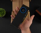 Een persoon die de Intel Arc Pro B50 low-profile workstation GPU met een blower-style koeler vasthoudt, afgebeeld tegen de verpakkingsdoos. (Afbeeldingsbron: ETA Prime via YouTube)
