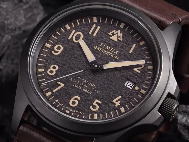 Close-up van de gestructureerde zwarte wijzerplaat van de Timex Expedition Field Post Titanium met Arabische cijfers, lichtgevende wijzers en indexen, en een datumvenster.